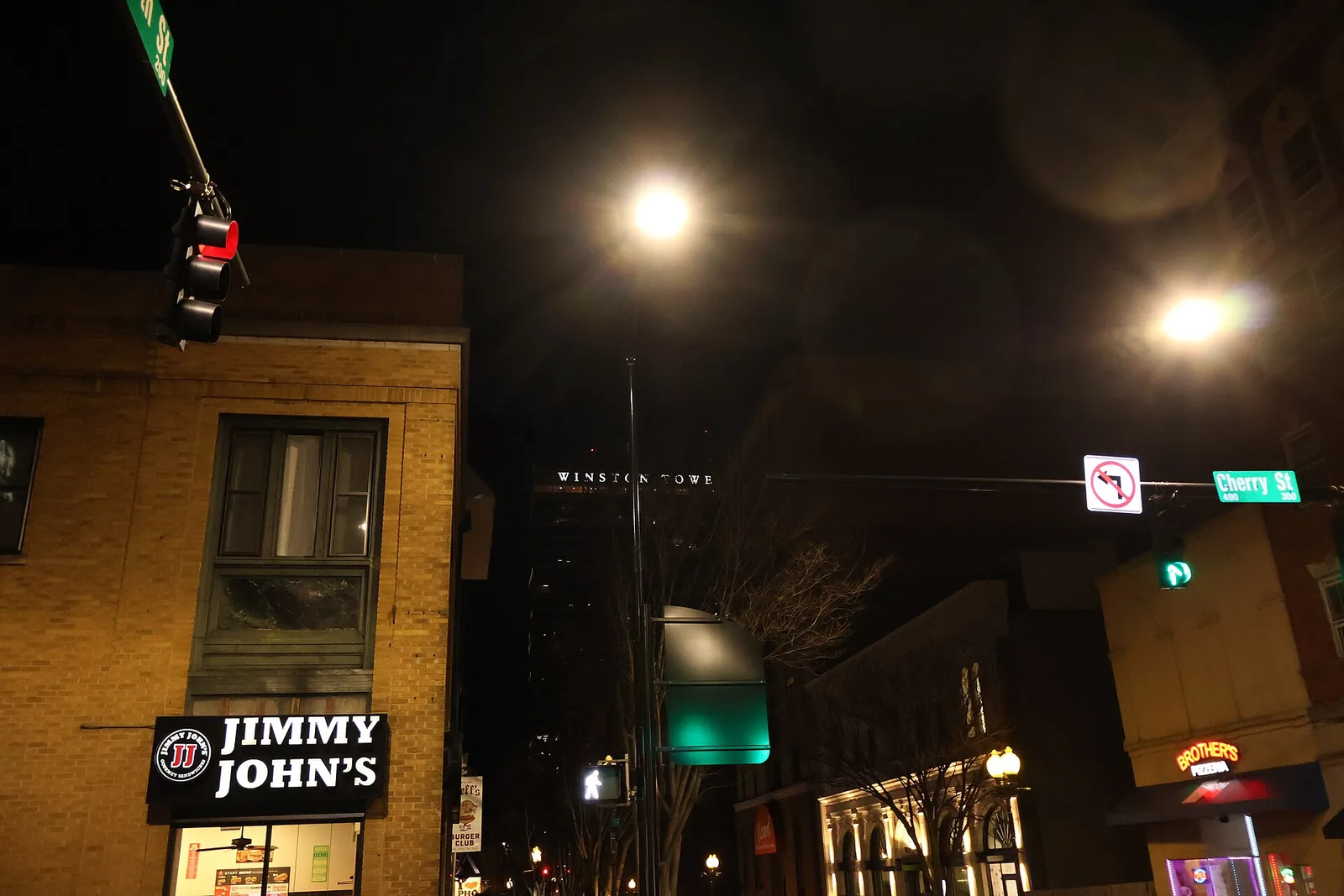 Restaurant lights at Cherry and Fourth streets in downtown Winston-Salem after dark, with the Winston Tower behind.