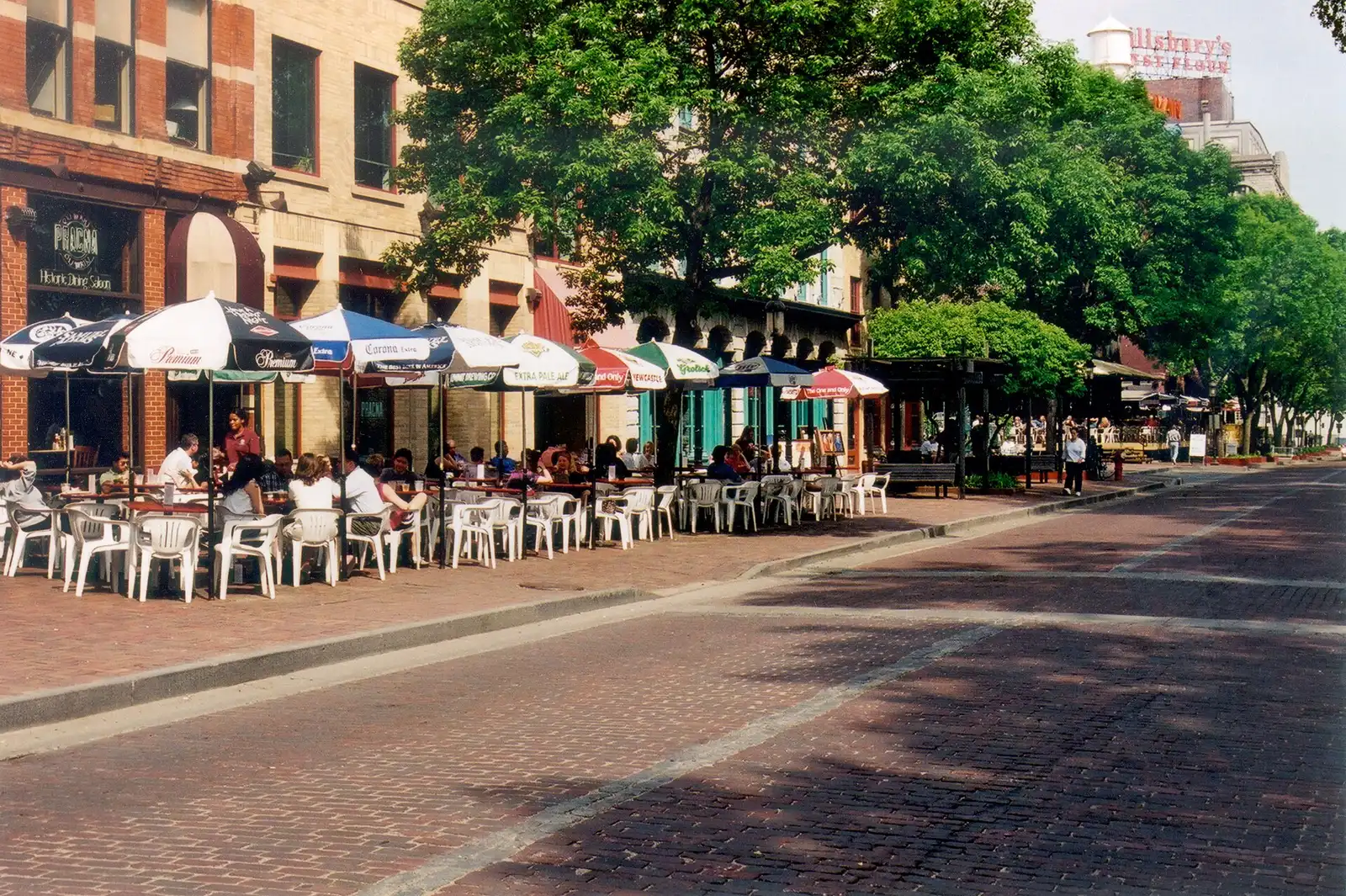 Diners at umbrella-shaded sidewalk tables outside restaurants in Minneapolis. The photo was not taken in Winston-Salem.
